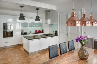 a kitchen with white cabinets and a vase of purple flowers at Veleslavinova - Old Town Apartment in Prague