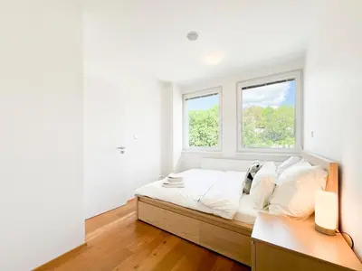 a white bedroom with a bed and two windows at Vila Grebovka in Prague