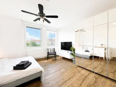 a white room with a bed and a ceiling fan at Vila Grebovka in Prague