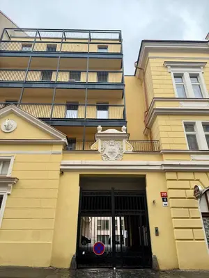 a yellow building with a black gate and a building at Apartment with free garage parking in Prague