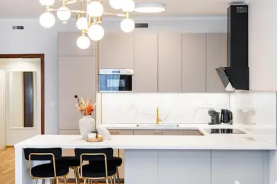 a white kitchen with white cabinets and black chairs at Rentero Spacious Smíchov 2 Bedroom Apartment with Excellent Tram Connection in Prague