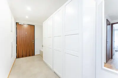 a hallway with white walls and a wooden door at Rentero Spacious Smíchov 2 Bedroom Apartment with Excellent Tram Connection in Prague