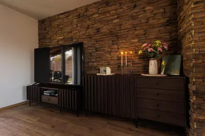 a living room with a television and a brick wall at Pool Villa Mukařov in Srbín