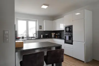 a kitchen with white cabinets and a counter with chairs at Pool Villa Mukařov in Srbín