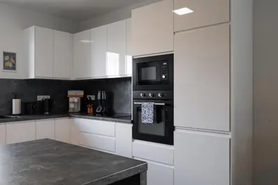 a kitchen with white cabinets and a black microwave at Pool Villa Mukařov in Srbín