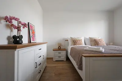 a bedroom with a bed and a dresser with flowers on it at Pool Villa Mukařov in Srbín