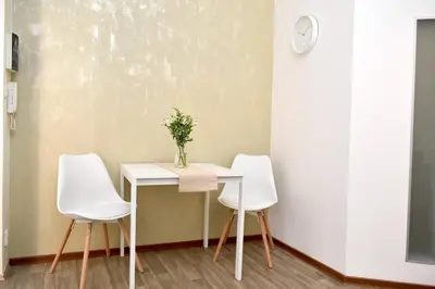 a table with three white chairs and a vase on it at Central one bedroom apartment in Prague