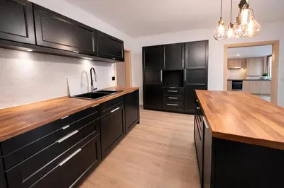 a kitchen with black cabinets and a wooden counter top at Family, party Apartament in Prague