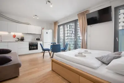 a bedroom with a large bed and a kitchen at Modern apartment with parking in Prague
