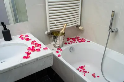 a bathroom with pink flowers on a counter next to a tub at White Rabbit's Residence in Prague