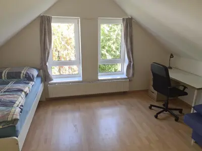 a bedroom with a bed and a desk and two windows at Rodinný dům v Praze s bazénem in Prague