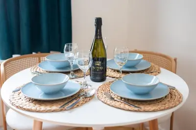 a white table with plates and a bottle of wine at Central City Apartments in Prague
