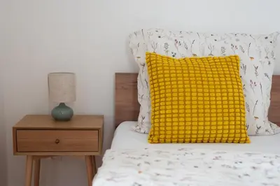 a yellow pillow on a bed next to a night stand at Central City Apartments in Prague