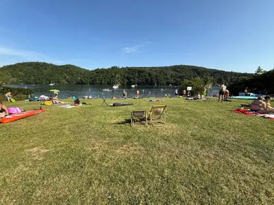 a group of people sitting in the grass at a lake at Apartmán Slapy - Ždáň in Slapy