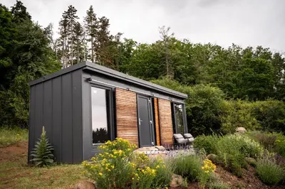 a black tiny house in the middle of a garden at Tiny House Sedla in Velká