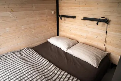 a bed in a room with a wooden wall at Tiny House Sedla in Velká