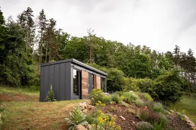 a black and grey shed in a garden at Tiny House Sedla in Velká