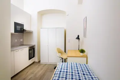 a small white kitchen with a desk and a table at Sokol House New Town in Prague