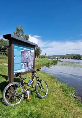 a bike parked next to a sign next to a river at Apartmán Maria in Litoměřice