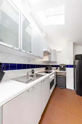 a white kitchen with a sink and a refrigerator at Cozy Luxe Home at the Heart of Old Prague Centre in Prague