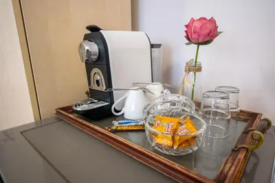 a table with a coffee maker and a flower on it at Hotel Junior Poděbrady in Poděbrady