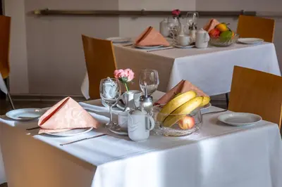 a table with a white table cloth with a bowl of fruit at Hotel Junior Poděbrady in Poděbrady