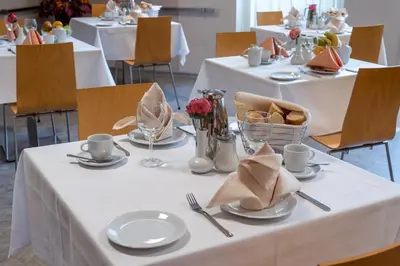 a table with white table cloths and plates on it at Hotel Junior Poděbrady in Poděbrady