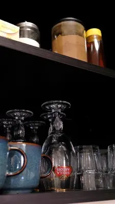 a shelf with glasses and jars on it at Modern apartment in Zizkov 10 min from Wenceslav Square in Prague