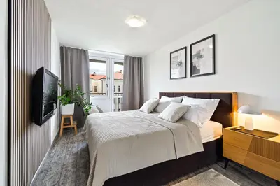 a white bedroom with a bed and a tv at Boutique apartment Záhřebská in Prague