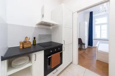 a kitchen with white cabinets and a black stove top oven at Dušní Street Gem in Prague