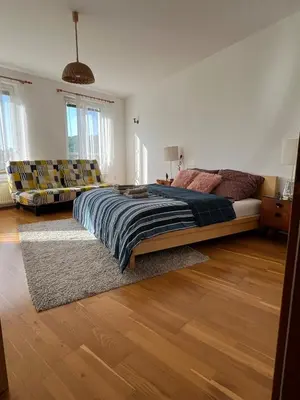 a bedroom with a large bed and chairs in it at A large 1 bedroom apartment with an available private parking in Prague