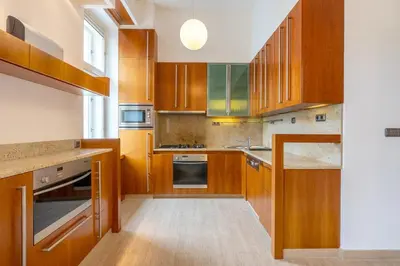 a kitchen with wooden cabinets and a large window at Bright OldTown 2bdr apartment in Prague