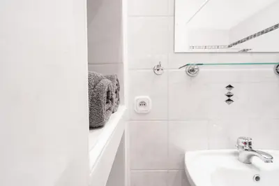 a white bathroom with a sink and a mirror at Tram Depot Loft in Prague