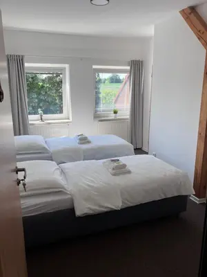 two beds in a bedroom with two windows at Dvůr Stupice
