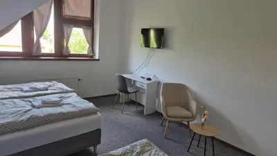 a bedroom with a bed and a desk with two chairs at Hotel Radnice Dobrovice in Dobrovice
