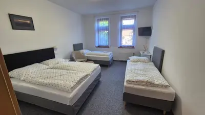 a room with three beds and a chair and windows at Hotel Radnice Dobrovice in Dobrovice