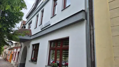 a white building with red windows on a street at Hotel Radnice Dobrovice in Dobrovice