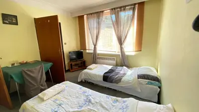a room with two beds and a table and a window at ALEX-ASIE-EU penzion in Unhošť