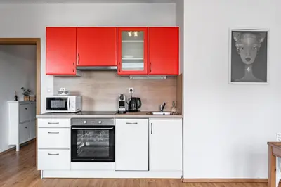 a kitchen with red cabinets and a microwave at Airport Apartman Víšek in Chýně