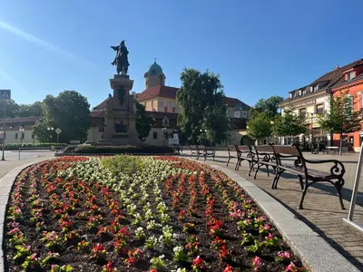 a park with benches and a statue and flowers at myPoděbrady apartment in Poděbrady