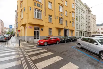 a yellow building with cars parked on the side of a street at Live like a local family in Letna in Prague