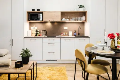 a kitchen with white cabinets and a table and chairs at Prague Days - One-bedroom Apartment with Netflix and High Speed WiFi in Karlín in Prague