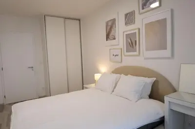 a bedroom with a white bed with pictures on the wall at Leo Cozy Flat Big Balcony Prague in Prague