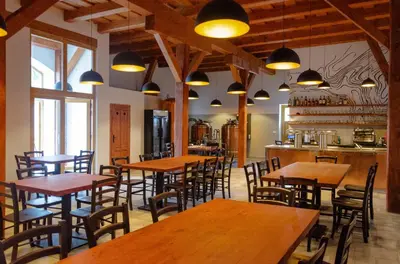 a restaurant with wooden tables and chairs and lights at Pivovar Kulivá Hora in Třebotov