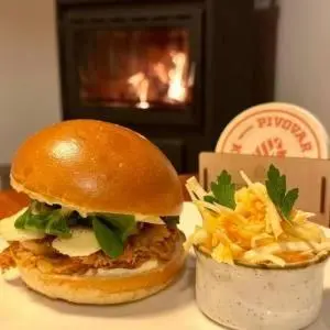 a sandwich and fries on a table with a fireplace at Pivovar Kulivá Hora in Třebotov