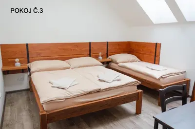 two twin beds in a room with wooden walls at Pivovar Kulivá Hora in Třebotov