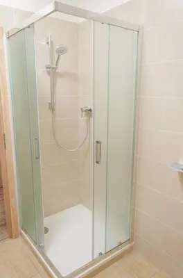 a shower with a glass door in a bathroom at Pivovar Kulivá Hora in Třebotov