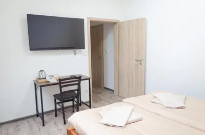 a room with two beds and a desk and a television at Pivovar Kulivá Hora in Třebotov