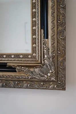 an ornate mirror with a wooden frame on a wall at Modern Deluxe Suite in Prague