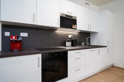 a kitchen with white cabinets and a microwave at Modern Deluxe Suite in Prague